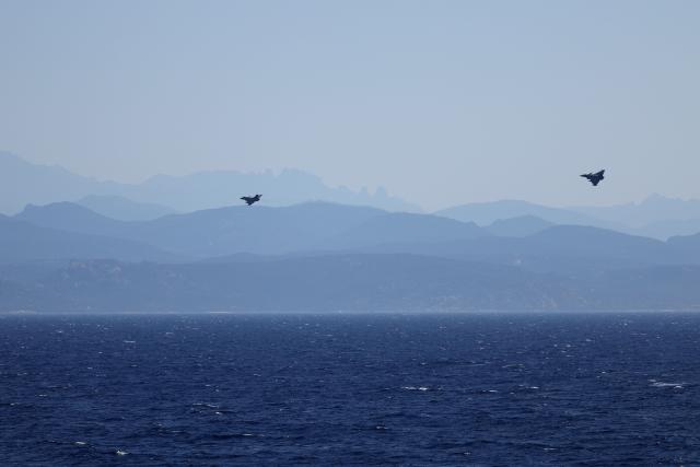 Two Marine Rafale airplanes fly over the Mediterranean Sea with the Corsica island in the background after taking off from the Charles de Gaulle Aircraft carrier coming back from its Lafayette 26 mission near Bonifacio of the French island of Corsica, southern France, on July 10, 2026. (Photo by Pascal POCHARD-CASABIANCA / AFP)