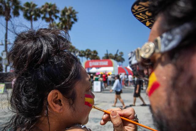Spain fans paint their faces in the colors of their national flag as they aattend a watch party for the World Cup quarterfinal match between Spain and Belgium at the Venice Beach FIFA Fan Festival in Venice, California, on July 10, 2026. (Photo by Apu GOMES / AFP)