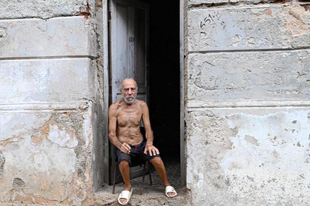 A man sits outside his home avoiding the heat and trying to connect to the internet amid a nationwide power outage on July 10, 2026. Cuba suffered its second nationwide blackout in five days on July 10 as twin energy and economic crises, compounded by a six-month US fuel blockade, caused the electricity grid to collapse. (Photo by ADALBERTO ROQUE / AFP)