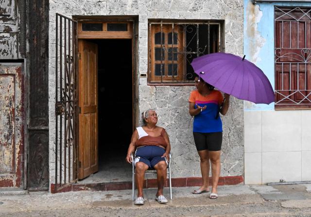 Two women remain poutside their home to avoid the heat during a nationwide power outage on July 10, 2026. Cuba suffered its second nationwide blackout in five days on July 10 as twin energy and economic crises, compounded by a six-month US fuel blockade, caused the electricity grid to collapse. (Photo by YAMIL LAGE / AFP)