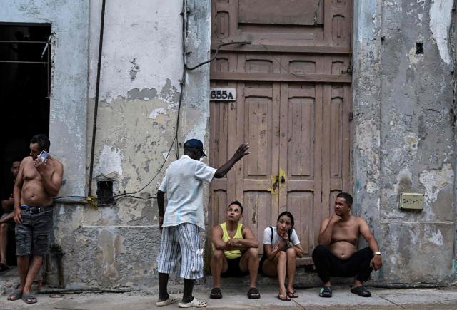 People sit at the doorstep to avoid the heat during a nationwide power outage on July 10, 2026. Cuba suffered its second nationwide blackout in five days on July 10 as twin energy and economic crises, compounded by a six-month US fuel blockade, caused the electricity grid to collapse. (Photo by YAMIL LAGE / AFP)