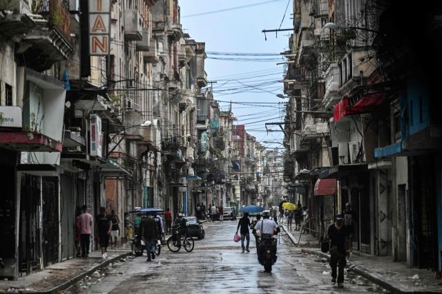 People walk along a street during a nationwide blackout in Havana on July 10, 2026. Cuba suffered its second nationwide blackout in five days on July 10 as twin energy and economic crises, compounded by a six-month US fuel blockade, caused the electricity grid to collapse. (Photo by YAMIL LAGE / AFP)