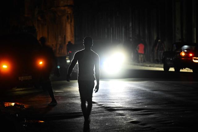 A man walks along a street during a nationwide blackout in Havana on July 10, 2026. Cuba suffered its second nationwide blackout in five days on July 10 as twin energy and economic crises, compounded by a six-month US fuel blockade, caused the electricity grid to collapse. (Photo by YAMIL LAGE / AFP)