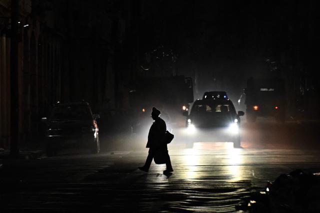 A person crosses a street during a nationwide blackout in Havana on July 10, 2026. Cuba suffered its second nationwide blackout in five days on July 10 as twin energy and economic crises, compounded by a six-month US fuel blockade, caused the electricity grid to collapse. (Photo by YAMIL LAGE / AFP)
