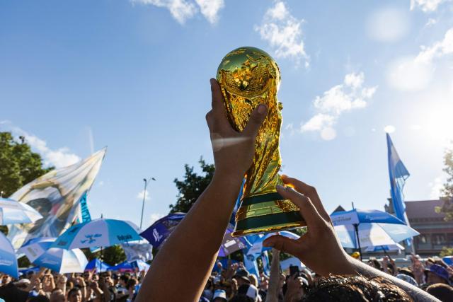 A replica of the FIFA World Cup is lifted by an Argentina's fan during a gathering at Mill Creek Park on the eve of the World Cup quarterfinal match between Argentina and Switzerland, in Kansas City, Missouri, on July 10, 2026. (Photo by Austin Johnson / AFP)