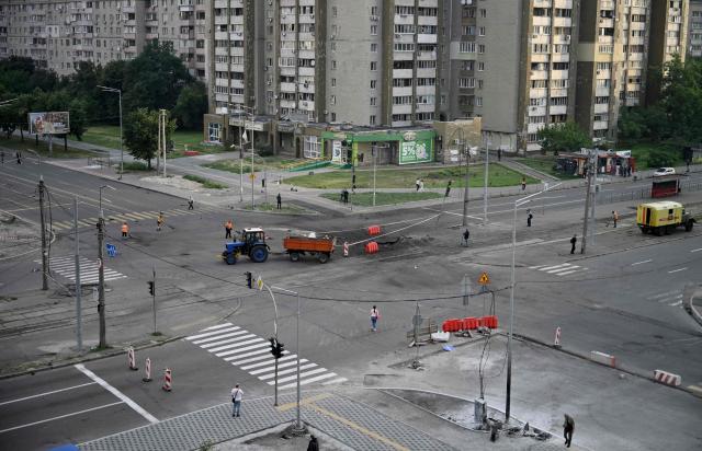 Communal workers clean around a crater from Russian missile strikes on the Ukrainian capital of Kyiv early on July 11, 2026, amid the Russian invasion in Ukraine. Ukraine said Russian missile strikes on Kyiv wounded six people, as Moscow escalates attacks on the Ukrainian capital. AFP journalists in Kyiv heard two series of explosions in the early hours of Saturday, with an air alert siren sounding minutes after the first blast. (Photo by Genya Savilov / AFP)