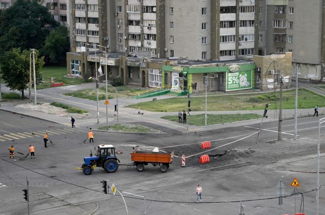 Communal workers clean around a crater from Russian missile strikes on the Ukrainian capital of Kyiv early on July 11, 2026, amid the Russian invasion in Ukraine. Ukraine said Russian missile strikes on Kyiv wounded six people, as Moscow escalates attacks on the Ukrainian capital. AFP journalists in Kyiv heard two series of explosions in the early hours of Saturday, with an air alert siren sounding minutes after the first blast. (Photo by Genya Savilov / AFP)