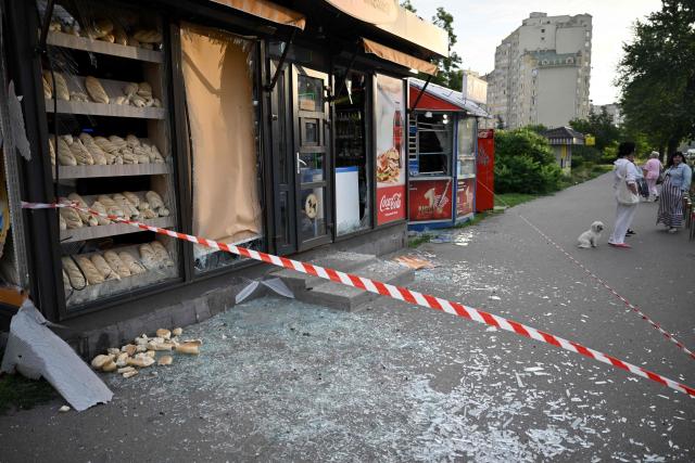 People stand abyt bread stall damaged as a result of Russian missile strikes on the Ukrainian capital of Kyiv early on July 11, 2026, amid the Russian invasion in Ukraine. Ukraine said Russian missile strikes on Kyiv wounded six people, as Moscow escalates attacks on the Ukrainian capital. AFP journalists in Kyiv heard two series of explosions in the early hours of Saturday, with an air alert siren sounding minutes after the first blast. (Photo by Genya Savilov / AFP)