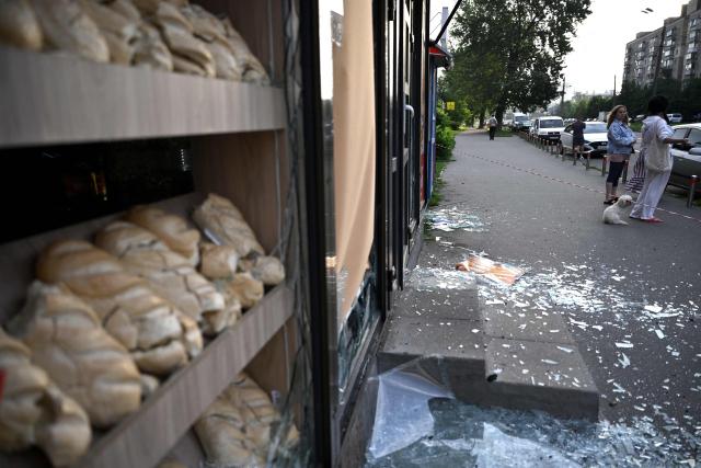 People stand abyt bread stall damaged as a result of Russian missile strikes on the Ukrainian capital of Kyiv early on July 11, 2026, amid the Russian invasion in Ukraine. Ukraine said Russian missile strikes on Kyiv wounded six people, as Moscow escalates attacks on the Ukrainian capital. AFP journalists in Kyiv heard two series of explosions in the early hours of Saturday, with an air alert siren sounding minutes after the first blast. (Photo by Genya Savilov / AFP)