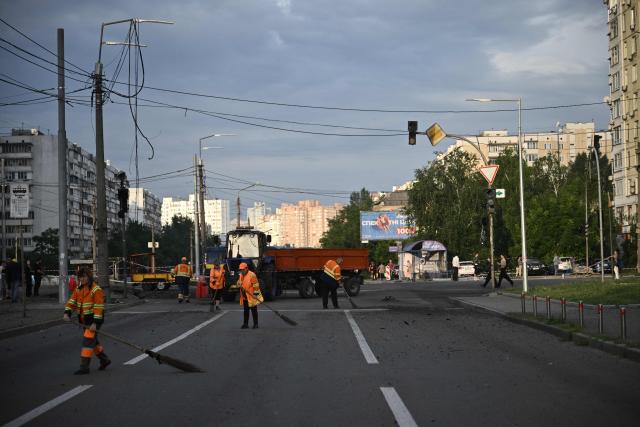 Communal workers clean around a crater from Russian missile strikes on the Ukrainian capital of Kyiv early on July 11, 2026, amid the Russian invasion in Ukraine. Ukraine said Russian missile strikes on Kyiv wounded six people, as Moscow escalates attacks on the Ukrainian capital. AFP journalists in Kyiv heard two series of explosions in the early hours of Saturday, with an air alert siren sounding minutes after the first blast. (Photo by Genya Savilov / AFP)