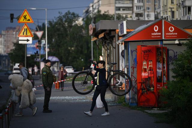 People walk past a bread stall damaged following a Russian missile strike on the Ukrainian capital of Kyiv early on July 11, 2026, amid the Russian invasion in Ukraine. Ukraine said Russian missile strikes on Kyiv wounded six people, as Moscow escalates attacks on the Ukrainian capital. AFP journalists in Kyiv heard two series of explosions in the early hours of July 11, with an air alert siren sounding minutes after the first blast. (Photo by Genya SAVILOV / AFP)