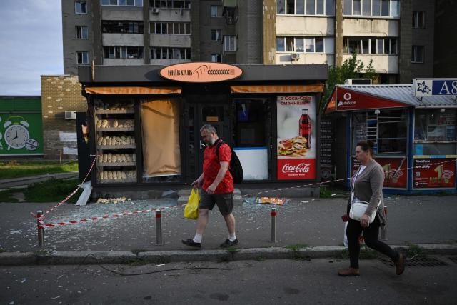 People walk past a bread stall damaged following a Russian missile strike on the Ukrainian capital of Kyiv early on July 11, 2026, amid the Russian invasion in Ukraine. Ukraine said Russian missile strikes on Kyiv wounded six people, as Moscow escalates attacks on the Ukrainian capital. AFP journalists in Kyiv heard two series of explosions in the early hours of July 11, with an air alert siren sounding minutes after the first blast. (Photo by Genya SAVILOV / AFP)
