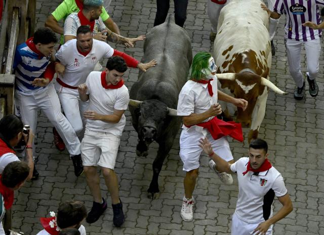Participants run ahead of bulls during the fifth running of the bulls of the San Fermin festival in Pamplona, northern Spain, on July 11, 2026. Thousands of people every year attend the week-long festival and its famous 'encierros', or running of the bulls, in which six bulls are released at 8:00 a.m. evey day to run from their corral to the bullring through the narrow streets of the old town over an 850 meters (yards) course while runners ahead of them try to stay close to the bulls without falling over or being gored. (Photo by ANDER GILLENEA / AFP)