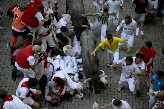 Participants fall as they run ahead of bulls during the fifth running of the bulls of the San Fermin festival in Pamplona, northern Spain, on July 11, 2026. Thousands of people every year attend the week-long festival and its famous 'encierros', or running of the bulls, in which six bulls are released at 8:00 a.m. evey day to run from their corral to the bullring through the narrow streets of the old town over an 850 meters (yards) course while runners ahead of them try to stay close to the bulls without falling over or being gored. (Photo by ANDER GILLENEA / AFP)