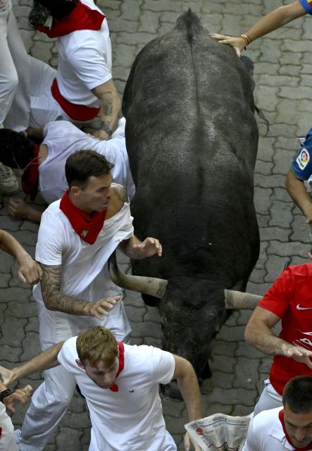 Participants run ahead of bulls during the fifth running of the bulls of the San Fermin festival in Pamplona, northern Spain, on July 11, 2026. Thousands of people every year attend the week-long festival and its famous 'encierros', or running of the bulls, in which six bulls are released at 8:00 a.m. evey day to run from their corral to the bullring through the narrow streets of the old town over an 850 meters (yards) course while runners ahead of them try to stay close to the bulls without falling over or being gored. (Photo by ANDER GILLENEA / AFP)