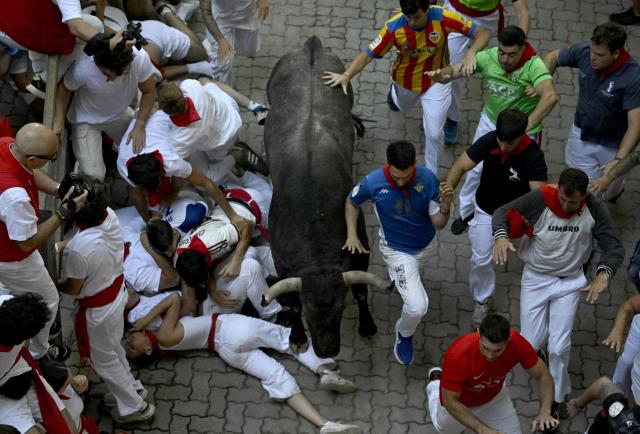Participants run ahead of bulls during the fifth running of the bulls of the San Fermin festival in Pamplona, northern Spain, on July 11, 2026. Thousands of people every year attend the week-long festival and its famous 'encierros', or running of the bulls, in which six bulls are released at 8:00 a.m. evey day to run from their corral to the bullring through the narrow streets of the old town over an 850 meters (yards) course while runners ahead of them try to stay close to the bulls without falling over or being gored. (Photo by ANDER GILLENEA / AFP)