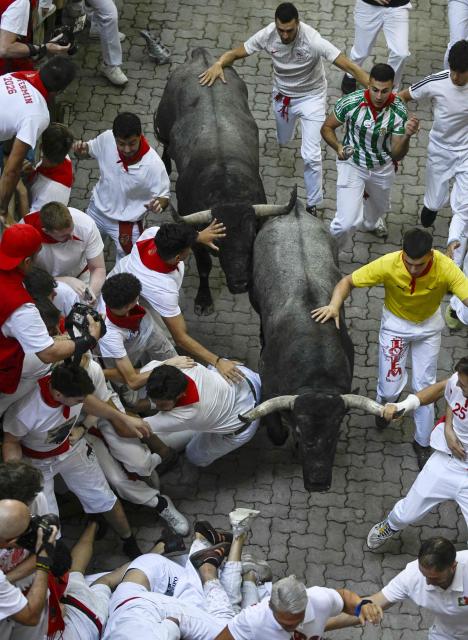 Participants run with the bulls during the fifth running of the bulls of the San Fermin festival in Pamplona, northern Spain, on July 11, 2026. Thousands of people every year attend the week-long festival and its famous 'encierros', or running of the bulls, in which six bulls are released at 8:00 a.m. evey day to run from their corral to the bullring through the narrow streets of the old town over an 850 meters (yards) course while runners ahead of them try to stay close to the bulls without falling over or being gored. (Photo by ANDER GILLENEA / AFP)