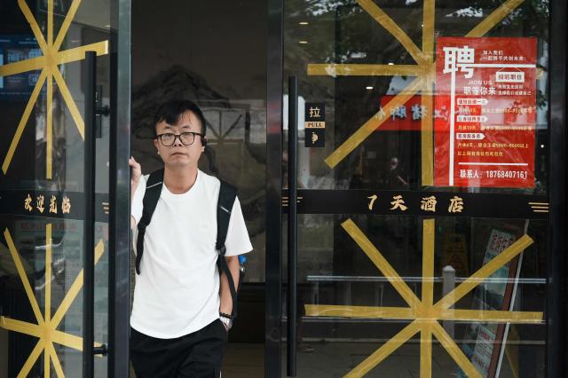 A man walks through a door with taped glass as people prepare for the approaching Typhoon Bavi to hit the region, in Hangzhou, China's eastern province, on July 11, 2026. (Photo by CN-STR / AFP) / China OUT