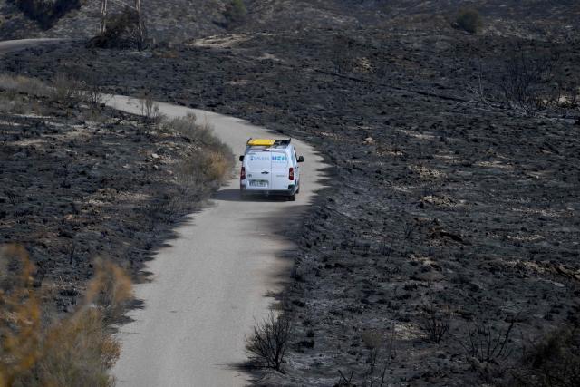 A car drives in a burnt landscape after a wildfire that killed at least 12 people, in Bedar, near Almeria, on July 11, 2026. A wildfire that has killed at least 12 people in southern Spain has burned about 6,600 hectares (16,300 acres) since July 9 but conditions improved during the night, the regional emergency services chief said on July 11. (Photo by JOSE JORDAN / AFP)