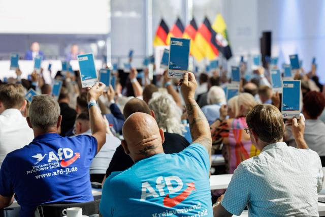 Delegates raise their voting cards during the state party convention of far-right Alternative for Germany party (AfD) in Magdeburg, eastern Germany on July 11, 2026. At its party conference, the AfD presented its 100-day programme for the period following the state election scheduled for September 6, 2026. (Photo by Jens SCHLÜTER / AFP)