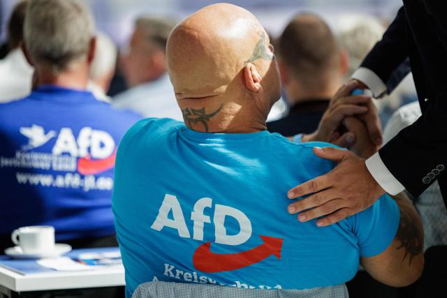 A delegate with a tattoo on his neck greets another delegate as they attend the state party convention of the far-right Alternative for Germany party (AfD) in Magdeburg, eastern Germany on July 11, 2026. At its party conference, the AfD presented its 100-day programme for the period following the state election scheduled for September 6, 2026. (Photo by Jens SCHLÜTER / AFP)