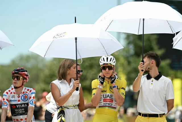 UAE Team Emirates - XRG's Slovenian rider Tadej Pogacar wearing the overall leader's yellow jersey (C) and Team Visma | Lease a Bike's Danish rider Jonas Vingegaard wearing the climber's dotted "King of the Mountains" jersey (L) shelter from the sun under umbrellas as they await the start of the 8th stage of the 113th edition of the Tour de France cycling race, 182 km between Périgueux and Bergerac in southwestern France, on July 11, 2026. (Photo by Loic VENANCE / AFP)