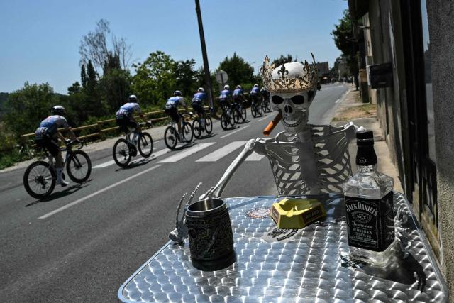 The pack of riders (peloton) cycles past a skeleton mannequin set up along the race route during the 8th stage of the 113th edition of the Tour de France cycling race, 180,4 km between Perigueux and Bergerac in southwestern France, on July 11, 2026. (Photo by Jeff PACHOUD / AFP)