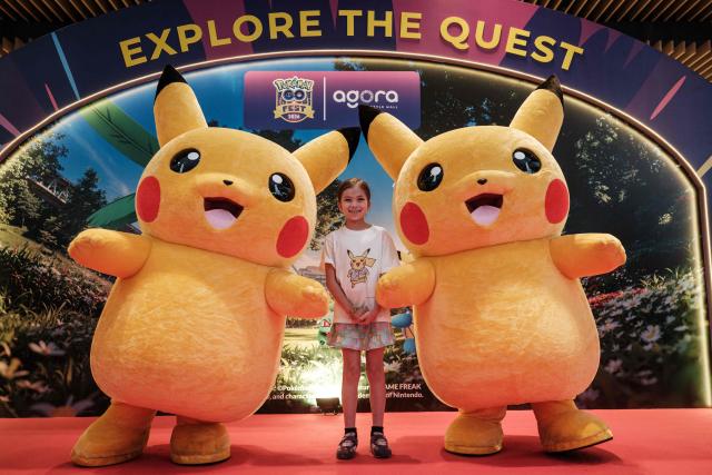 Two Pikachu mascots pose for a photograph with a girl during 'Pokemon GO Fest: Global', a worldwide event marking the 10th anniversary of Pokemon GO, an augmented reality mobile game, at Agora Mall in Jakarta on July 11, 2026. (Photo by YASUYOSHI CHIBA / AFP)