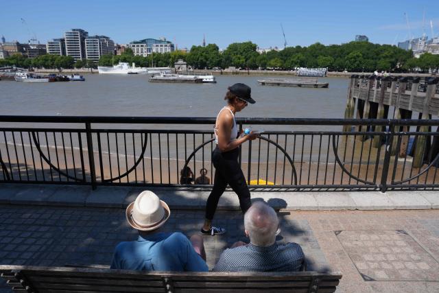 People sit in the shade of a tree as they look out over the River Thames, in central London on July 11, 2026, as the British capital continues to experience high temperatures. Britain's Met office said on July 9, that the UK had experienced its eighth day in 2026 with the mercury climbing above 34C, breaking the previous record by one day. (Photo by CARLOS JASSO / AFP)