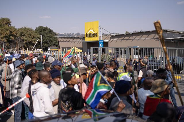 Protesters gather in front a Builders hardware store during an anti-migration demonstration in Norwood on July 11, 2026. Protests that began with groups like March and March have since spread to ordinary residents taking to the streets, as anti-migrant sentiment continues to spread across South Africa. (Photo by EMMANUEL CROSET / AFP)