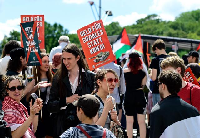 Demonstrators hold placards reading "No to compulsory military service" (L) and "Money for social welfare rather than for war" (R), as well as Palestinian flags, during an anti-war and anti-military service demonstration organised by an action group against German arms manufacturer Rheinmetall planning to construct an ammunition plant in the Wedding district of the German capital, in Berlin, Germany, on July 11, 2026. (Photo by Tobias SCHWARZ / AFP)