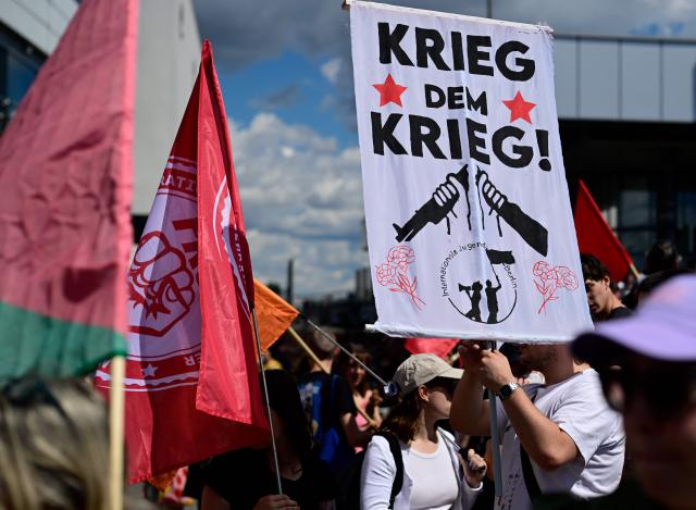A demonstrator holds a banner reading "War on war!" during an anti-war and anti-military service demonstration organised by an action group against German arms manufacturer Rheinmetall planning to construct an ammunition plant in the Wedding district of the German capital, in Berlin, Germany, on July 11, 2026. (Photo by Tobias SCHWARZ / AFP)