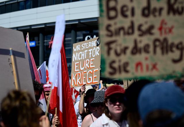 A demonstrator holds a placard reading "We won't die for your wars" during an anti-war and anti-military service demonstration organised by an action group against German arms manufacturer Rheinmetall planning to construct an ammunition plant in the Wedding district of the German capital, in Berlin, Germany, on July 11, 2026. (Photo by Tobias SCHWARZ / AFP)