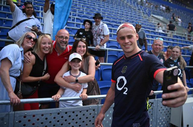 England's centre Seb Atkinson (R), with a blood-stained bandage on his head, takes a selfie with fans after the Rugby Union Nations Championship match between Fiji and England at Hill Dickinson Stadium in Liverpool on July 11, 2026. England won the match 73-8. (Photo by Oli SCARFF / AFP)