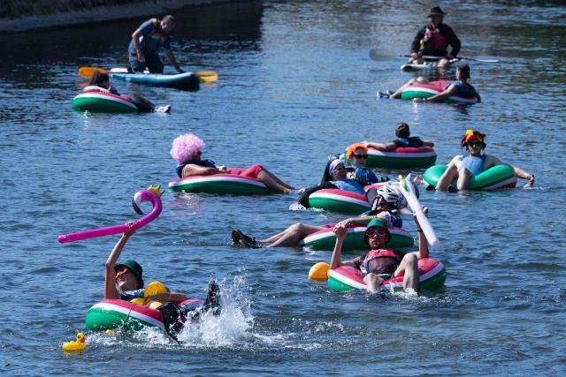 Participants in the "Mascarets" festival float down the Risle River on inner tubes during a heatwave in Pont-Audemer on July 11, 2026. The European nation is facing its third heatwave since May, with a part of western France under the more severe heat warning on July 10, 2026 and fires raging in several parts of the country over the past week. (Photo by Joel Saget / AFP)