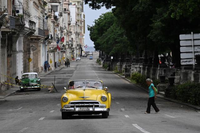 People and vehicles are seen along a street in Havana on July 11, 2026. Cuba suffered its second nationwide blackout in five days on July 10 as twin energy and economic crises, compounded by a six-month US fuel blockade, caused the electricity grid to collapse. (Photo by YAMIL LAGE / AFP)