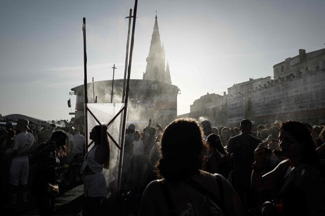 Festival-goers gather as water is sprayed to cool off the crowd in front of the Jean-Louis Foulquier stage during the 42nd Francofolies music festival, in La Rochelle, western France on July 11, 2026. (Photo by Philippe LOPEZ / AFP)