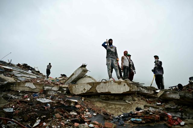 Rescuers stand on top of a large slab of collapsed concrete amid widespread debris Caraballeda, La Guaira state, Venezuela, on July 11, 2026, following twin earthquakes that struck the region. The death toll from the twin earthquakes that struck Venezuela on June 24 has risen to more than 4,300, National Assembly President Jorge Rodriguez said on July 11. (Photo by MARTIN BERNETTI / AFP)