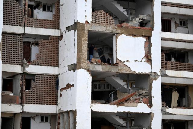 People salvage household belongings from a damaged residential building in Caraballeda, La Guaira state, Venezuela, on July 11, 2026, following twin earthquakes that struck the region. The death toll from the twin earthquakes that struck Venezuela on June 24 has risen to more than 4,300, National Assembly President Jorge Rodriguez said on July 11. (Photo by Raul ARBOLEDA / AFP)