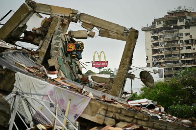 Collapsed structures and a damaged residential tower are seen in Caraballeda, La Guaira state, Venezuela, on July 11, 2026, following twin earthquakes that struck the region, with a McDonald's sign visible in the background. The death toll from the twin earthquakes that struck Venezuela on June 24 has risen to more than 4,300, National Assembly President Jorge Rodriguez said on July 11. (Photo by MARTIN BERNETTI / AFP)