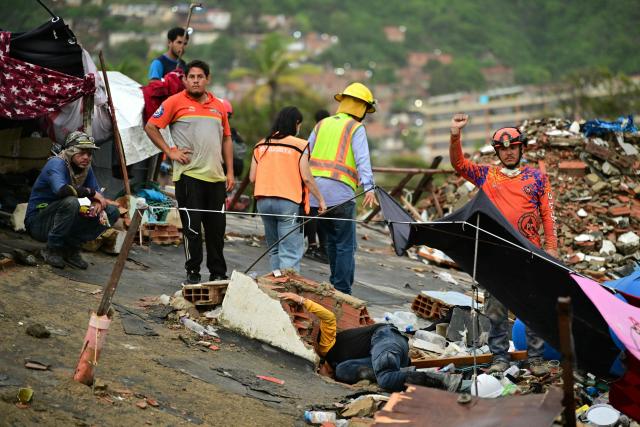 A rescue worker calls for silence as they search for possible survivors at the site of a collapsed building in Caraballeda, La Guaira state, Venezuela, on July 11, 2026, following twin earthquakes that struck the region. The death toll from the twin earthquakes that struck Venezuela on June 24 has risen to more than 4,300, National Assembly President Jorge Rodriguez said on July 11. (Photo by MARTIN BERNETTI / AFP)