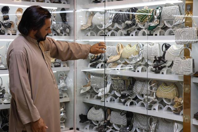 This photograph taken on June 30, 2026 shows an Afghan shopkeeper sorting women's shoes and handbags at a shopping centre in Herat. Businesses in Afghanistan's western city of Herat have suffered from a downturn in female customers opting to stay home following a recent crackdown by morality police on women's attire, according to shopkeepers, drivers and residents. (Photo by Mohsen KARIMI / AFP)