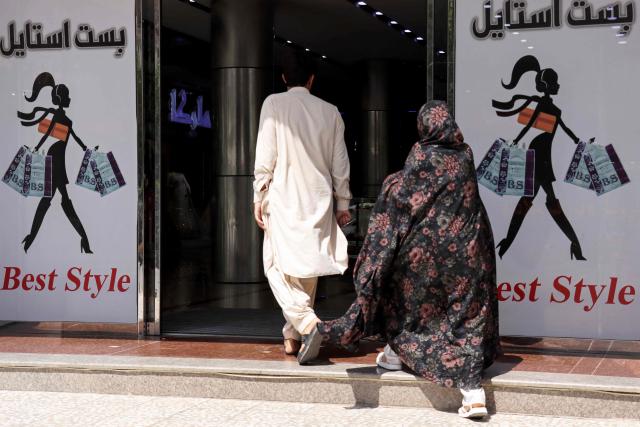 This photograph taken on July 1, 2026 shows an Afghan man and a woman entering a shopping centre in Herat. Businesses in Afghanistan's western city of Herat have suffered from a downturn in female customers opting to stay home following a recent crackdown by morality police on women's attire, according to shopkeepers, drivers and residents. (Photo by Mohsen KARIMI / AFP)