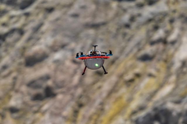 This picture shows a drone with a mirror used to reflect a laser and collect data from gas emissions flying above the crater of La Fossa, on Vulcano Island, one of the seven islands of the Aeolian Archipelago of Sicily, on July 9, 2026. A team of researchers from Germany are testing a new system for measuring volcanic gases to better anticipate future eruptions. Hovering over the crater of La Fossa, a drone positions itself in front of a laser beam set at the edge of the chasm on Vulcano, off Sicily, and collect data. (Photo by Marco Bertorello / AFP)