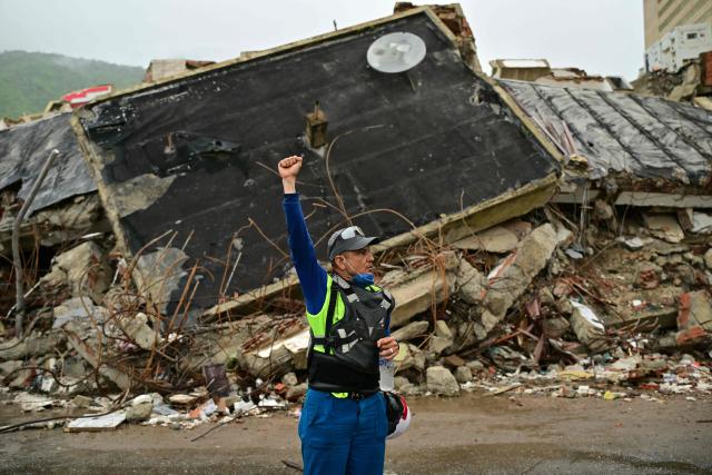 TOPSHOT - A rescue worker calls for silence during a search operation at the site of a collapsed building in Caraballeda, La Guaira state, Venezuela, on July 11, 2026, following twin earthquakes that struck the region. The death toll from the twin earthquakes that struck Venezuela on June 24 has risen to more than 4,300, National Assembly President Jorge Rodriguez said on July 11. (Photo by MARTIN BERNETTI / AFP)