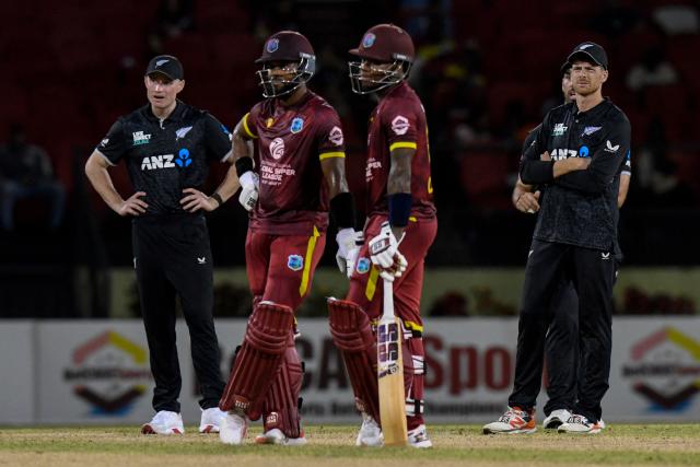 Matt Fisher (L) and Mitchell Santner (R) of New Zealand watch the screen as Shai Hope (2L) wawaits the third umpire's decision on Keacy Carty (3L) of West Indies during the first one-day international (ODI) cricket match between West Indies and New Zealand at Guyana National Stadium in Providence, Guyana on July 11, 2026. (Photo by Randy Brooks / AFP)