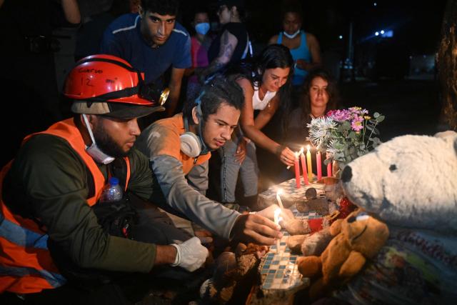 Volunteers, rescuers and residents light candles during a vigil in front of the rubble of the collapsed Obras del Poder Popular (OPP) building in Caraballeda, La Guaira state, Venezuela, on July 11, 2026, following twin earthquakes that struck the region. The death toll from the twin earthquakes that struck Venezuela on June 24 has risen to more than 4,300, National Assembly President Jorge Rodriguez said on July 11. (Photo by Juan BARRETO / AFP)