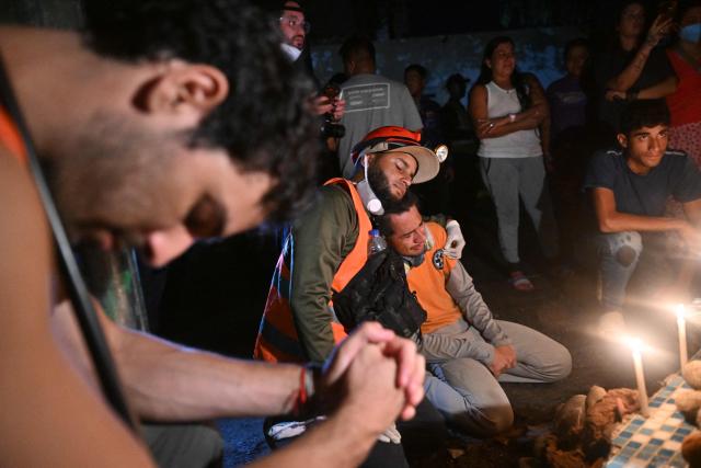 Volunteers, rescuers and residents light candles during a vigil in front of the rubble of the collapsed Obras del Poder Popular (OPP) building in Caraballeda, La Guaira state, Venezuela, on July 11, 2026, following twin earthquakes that struck the region. The death toll from the twin earthquakes that struck Venezuela on June 24 has risen to more than 4,300, National Assembly President Jorge Rodriguez said on July 11. (Photo by Juan BARRETO / AFP)