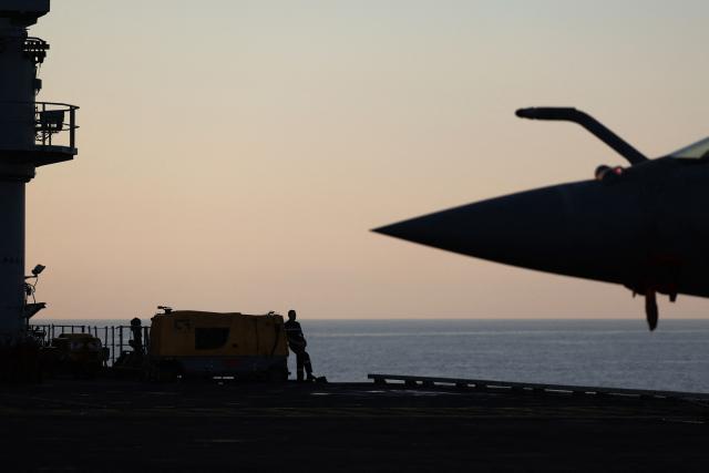 A French Navy officer stands on the flight deck of the Charles de Gaulle aircraft carrier, with a Marine Rafale fighter aircraft in the foreground, as it returns from its 'Lafayette 26' mission near Bonifacio off the coast of the French island of Corsica, southern France on July 9, 2026. (Photo by Pascal POCHARD-CASABIANCA / AFP)