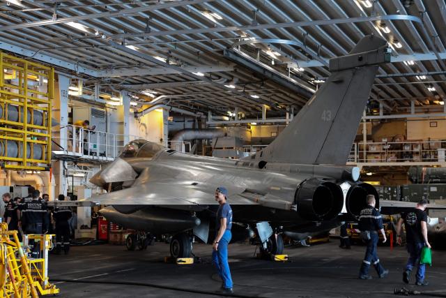 French Navy officers stand next to a Marine Rafale fighter aircraft on the hangar deck of the Charles de Gaulle aircraft carrier as it returns from its 'Lafayette 26' mission near Bonifacio off the coast of the French island of Corsica, southern France on July 9, 2026. (Photo by Pascal POCHARD-CASABIANCA / AFP)